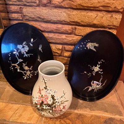 Sale Photo Thumbnail #101: Pair of Asian black lacquer oval trays with mother-of-pearl bird and floral inlays, displayed alongside a hand-painted ceramic vase.