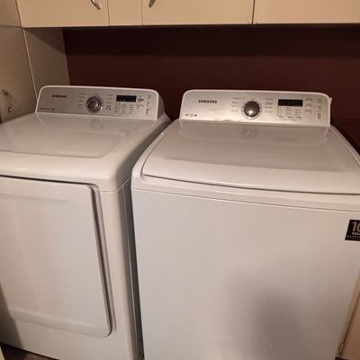 Sale Photo Thumbnail #38: Matching Samsung top-load washer and front-load dryer set in white, positioned beneath overhead cabinetry.