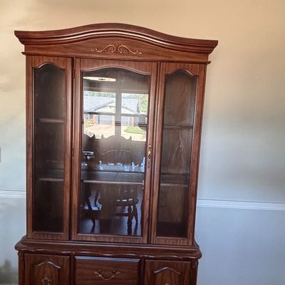 Sale Photo Thumbnail #147: Traditional dark wood china cabinet with arched glass display doors, carved accents, and lower storage drawers and cabinets.