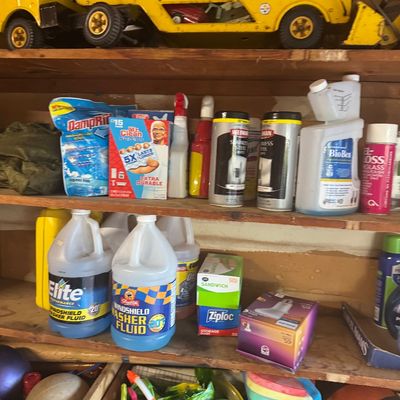 Sale Photo Thumbnail #85: Wooden garage shelving filled with vintage Tonka toy trucks, household cleaning supplies, windshield washer fluid, and various storage items.