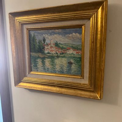 Sale Photo Thumbnail #152: Impressionist-style oil painting depicting a lakeside European village with a church tower, housed in an ornate gilded wood frame with a linen liner.