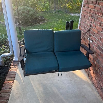 Sale Photo Thumbnail #118: Two-person wooden porch swing suspended by chains, featuring plush teal outdoor cushions.