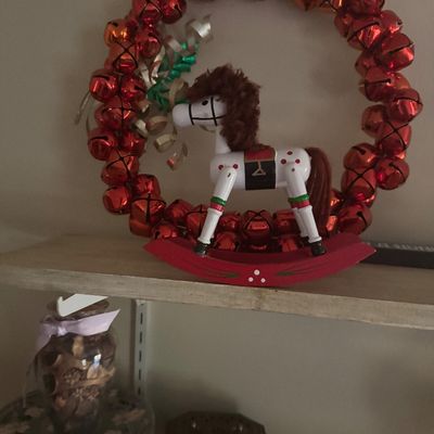 Sale Photo Thumbnail #72: Festive Christmas decoration featuring a red sleigh bell wreath framing a painted wooden rocking horse figurine with yarn mane.
