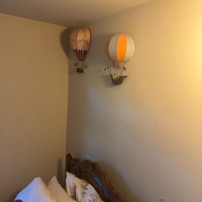 Sale Photo Thumbnail #59: Pair of vintage hot air balloon wall-mounted decorative sculptures hanging above a wooden bed frame.
