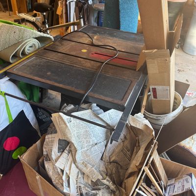 Sale Photo Thumbnail #101: Vintage table saw surrounded by miscellaneous garage items, packing material, and cardboard boxes.
