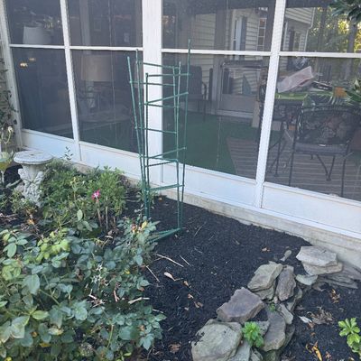 Sale Photo Thumbnail #126: Foldable green metal plant cages set in a garden bed alongside a stone border.