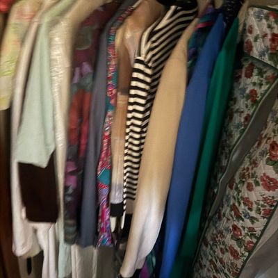 Sale Photo Thumbnail #35: Selection of vintage women's clothing and garment bags hanging in a closet, featuring colorful patterns and stripes.