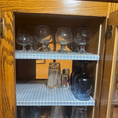 Sale Photo Thumbnail #222: Collection of assorted glassware, including snifters, tumblers, and shot glasses, stored inside a wooden cabinet.