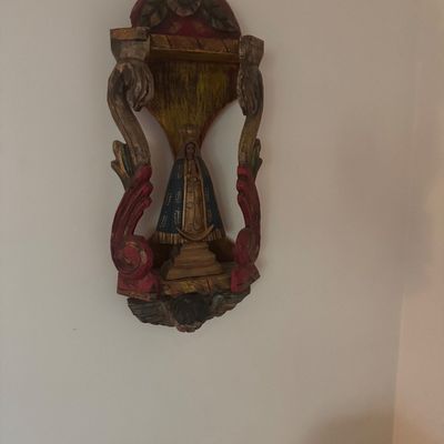 Sale Photo Thumbnail #147: Hand-carved and polychrome painted wooden religious shrine featuring a figure of the Virgin Mary housed within an ornate scrolled frame.
