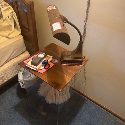 Sale Photo Thumbnail #61: Vintage brown metal gooseneck desk lamp resting on a wooden nightstand beside a wooden bed frame.