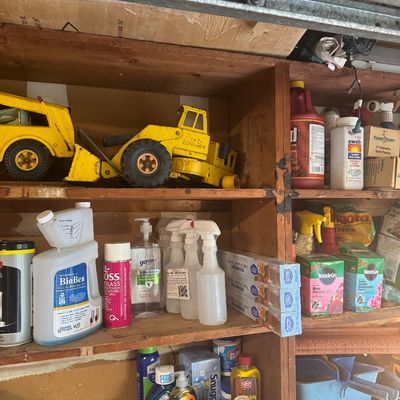 Sale Photo Thumbnail #86: Wooden garage shelving units stocked with vintage Tonka toy construction vehicles, household cleaning supplies, and lawn chemicals.