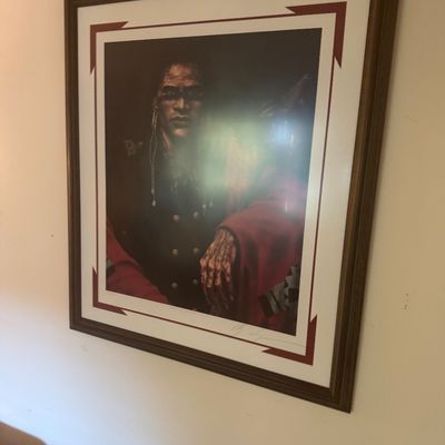 Sale Photo Thumbnail #177: Framed and matted artwork depicting a Native American figure, signed along the lower right border and housed in a dark wooden frame.
