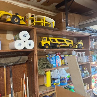 Sale Photo Thumbnail #89: Garage storage unit containing vintage Tonka pressed steel construction toys, car carriers, cleaning supplies, and household paper products.