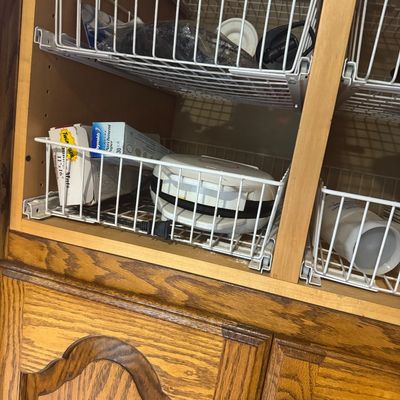 Sale Photo Thumbnail #217: Wooden kitchen cabinet filled with pull-out wire basket organizers containing kitchen supplies and small appliances like a George Foreman style grill.
