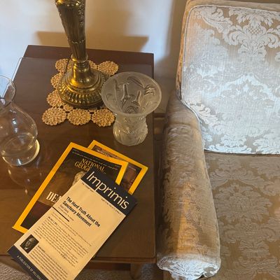 Sale Photo Thumbnail #165: Traditional brass table lamp and glass decor pieces on a wooden side table next to an upholstered damask armchair.