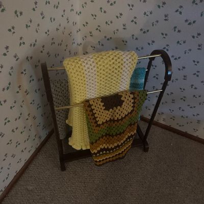 Sale Photo Thumbnail #27: Dark wooden blanket rack displaying an assortment of handmade vintage crocheted afghans and throws.