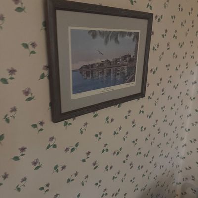 Sale Photo Thumbnail #28: Framed coastal art print depicting a waterfront village with reflections, set in a dark wood frame with grey matting.
