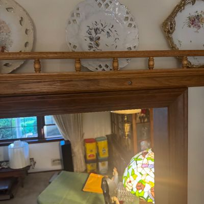Sale Photo Thumbnail #205: Collection of decorative vintage porcelain plates, including reticulated pierced-rim designs with floral motifs, displayed on a wooden shelf above a mirror.