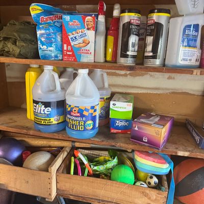 Sale Photo Thumbnail #84: Assorted household cleaning supplies, automotive fluids, Ziploc bags, and sports equipment arranged on wooden shelves.