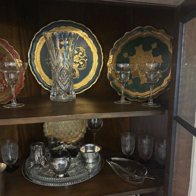 Sale Photo Thumbnail #210: Wooden display cabinet filled with vintage crystal glassware, silver-plated tea pieces, and ornate Florentine-style gilded decorative trays.