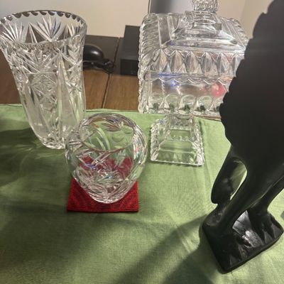 Sale Photo Thumbnail #191: Collection of clear cut glass tabletop items including a vase, a small rose bowl, and a pedestal candy dish with a lid, alongside a dark carved figurine.