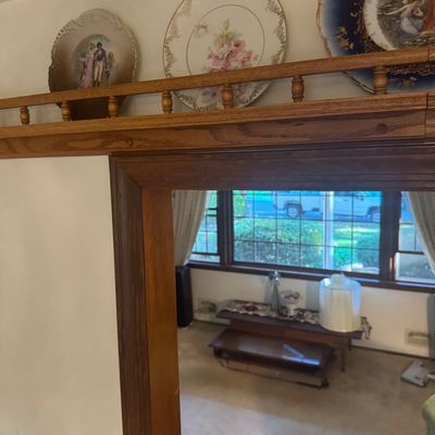 Sale Photo Thumbnail #202: Collection of ornate vintage decorative wall plates displaying romantic figures and floral motifs, arranged on a spindle-railed wooden plate shelf above a doorway.
