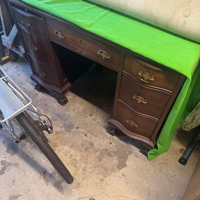 Sale Photo Thumbnail #79: Traditional dark wood kneehole desk featuring carved claw-and-ball feet, brass bail handles, and serpentine-front drawers.