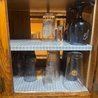 Sale Photo Thumbnail #219: Assorted glassware inside a grid-lined wooden hutch, including black stems and souvenir glasses like a Hard Rock Cafe tumbler.