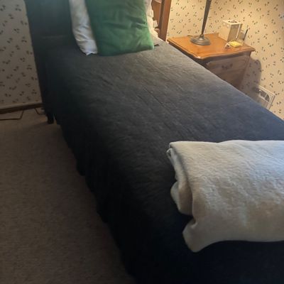 Sale Photo Thumbnail #17: Twin-size wooden bed frame with carved headboard, dark bedspread, and matching wooden nightstand with table lamp.