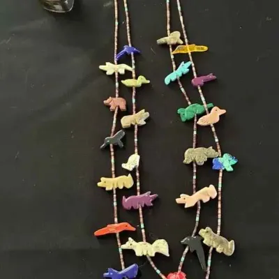 Sale Photo Thumbnail #2: Native American Zuni double-strand fetish necklace featuring hand-carved stone animal fetishes on liquid silver and bead strands, displayed next to a small metal container.