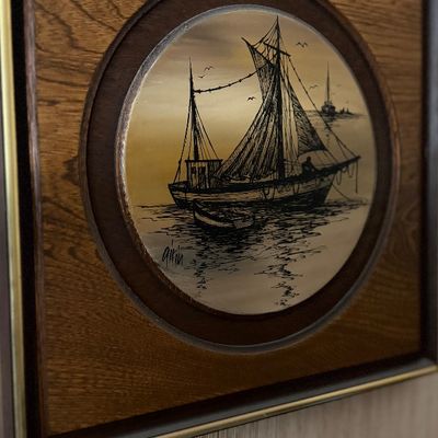 Vintage sailboat nautical art piece set in a circular frame within a wood-grain panel.