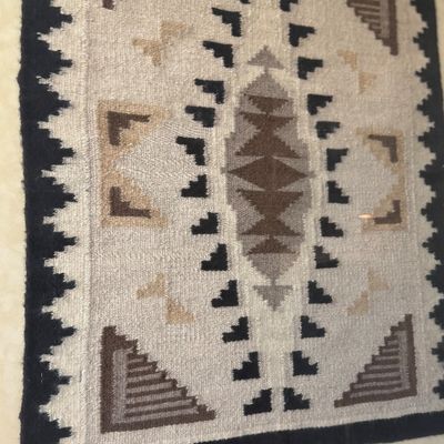 Framed Southwestern style woven textile with a geometric pattern in earth tones.