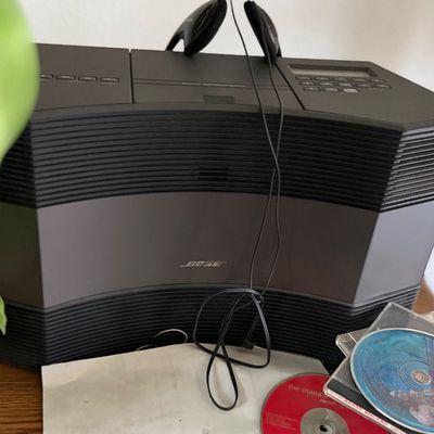 Bose Acoustic Wave music system with attached headphones and compact discs.
