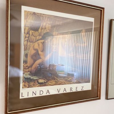 Sale Photo Thumbnail #145: Framed Linda Varez art poster featuring an illustration of an artisan at work, housed in a brown wood-look frame with gold accents.