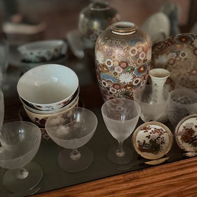 Collection of decorative collectibles and glassware inside a display cabinet, featuring a Japanese Satsuma-style floral vase and matching...