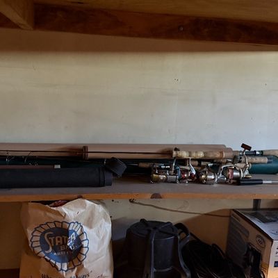 Sale Photo Thumbnail #163: Assortment of fishing rods, reels, and storage tubes displayed on a wooden garage shelf.
