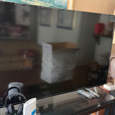 Large black flat-screen television set on a glass-topped media console table.