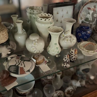 Display case filled with collectible ceramics, pottery, small vases, and decorative trinkets.