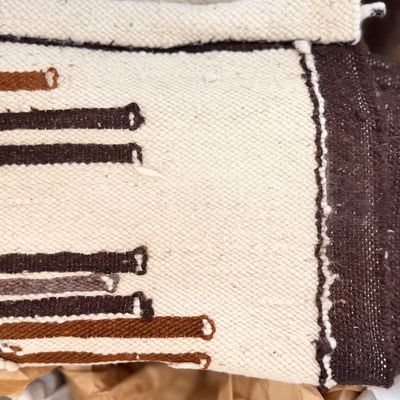 Sale Photo Thumbnail #141: Handwoven wool Southwest or Navajo style area rug folded, featuring a cream background with brown and rust geometric stripe designs.
