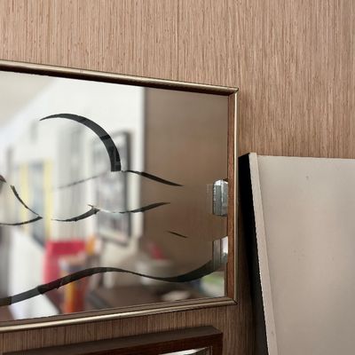 Small framed mirror with abstract wave artwork.