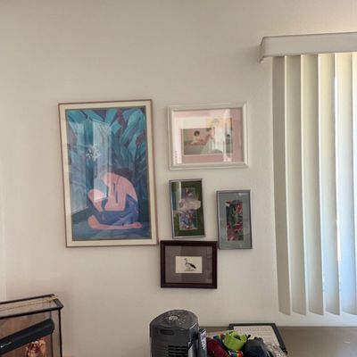 Sale Photo Thumbnail #147: Framed art print featuring a figure seated among tropical foliage in blue and pink tones.
