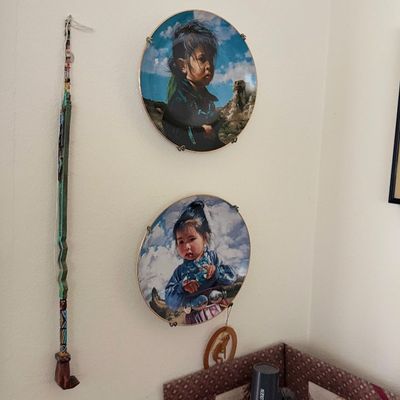 Sale Photo Thumbnail #152: Two decorative wall plates featuring Native American portraits, mounted on the wall alongside a beaded decorative staff.