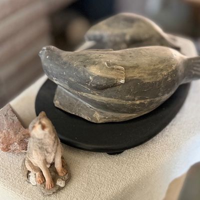 Carved soapstone seal sculpture displayed on a black wooden base.
