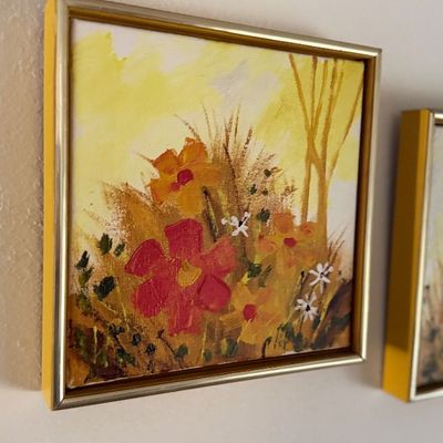 Sale Photo Thumbnail #103: Framed floral painting featuring impasto wildflowers in shades of red, yellow, and orange, housed in a thin metallic frame with a yellow painted outer edge.