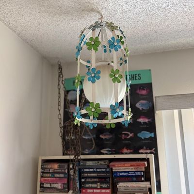 Sale Photo Thumbnail #118: Vintage 1960s-1970s flower power swag pendant light featuring a birdcage-style white metal frame adorned with blue and green painted metal flowers and a globe light diffuser.