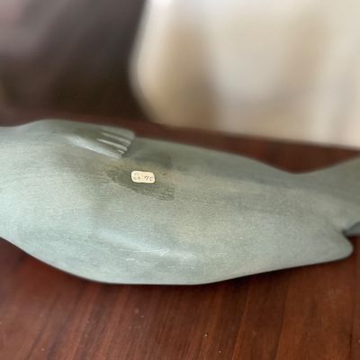 Hand-carved green soapstone seal figurine resting on a wooden surface.