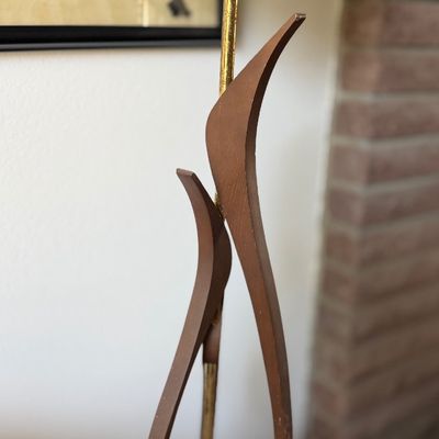 Mid-century modern table lamp featuring a sculptured bentwood flame motif body, brass accents, and a dark drum shade.