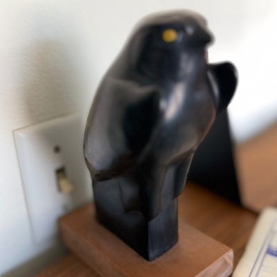 Sale Photo Thumbnail #116: Carved black stone or resin bird statue mounted on a rectangular wooden base.