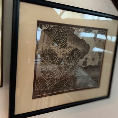 Framed Japanese-style print featuring a bird in flight over pine branches, presented in a black frame with a light mat.