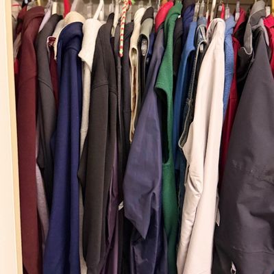 A closet filled with assorted jackets, hoodies, and outerwear hanging on a clothing rod.